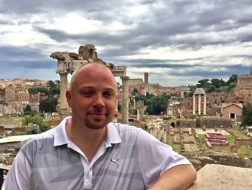Headshot of Michael Canaris in front of classic Italian ruins.