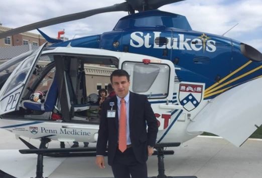 A male St. Lukes resident standing in front of a helicopter.