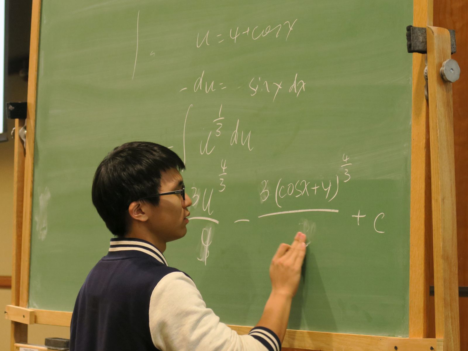 A male student solving a trigonometric integral at the blackboard during the 2018 Integration Bee