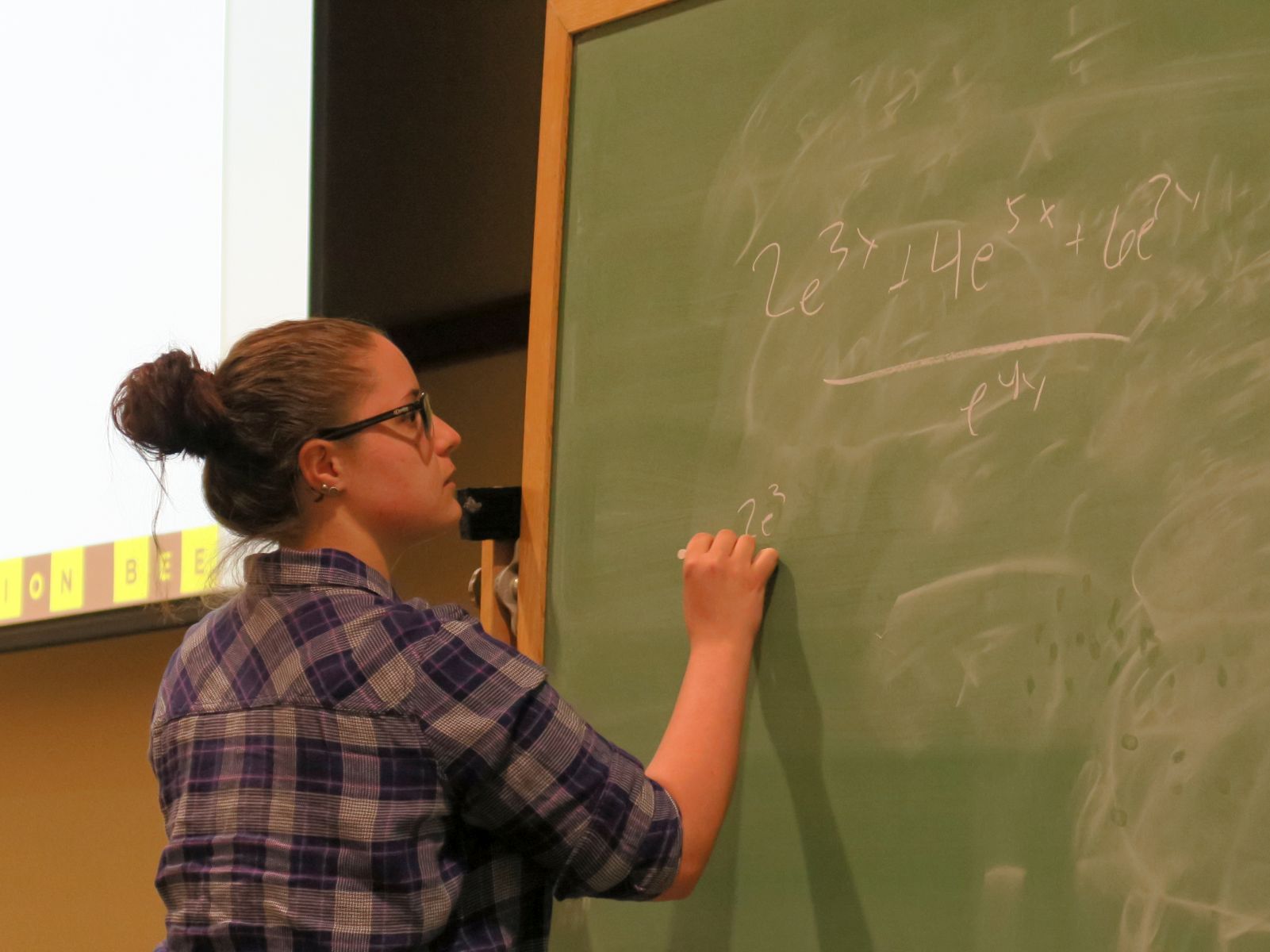 A female student solving an exponential integral at the blackboard during the 2018 Integration Bee