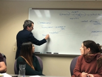 Man writing on whiteboard as student looks back