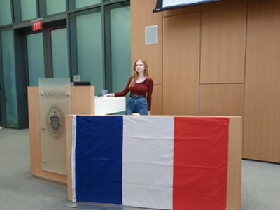 French FLTA, Audrey, standing at podium with French Flag