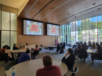 A group of students in a large room watching an anime movie.