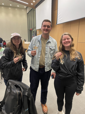  Three students holding handmade straw ornaments that are traditional in Germany.