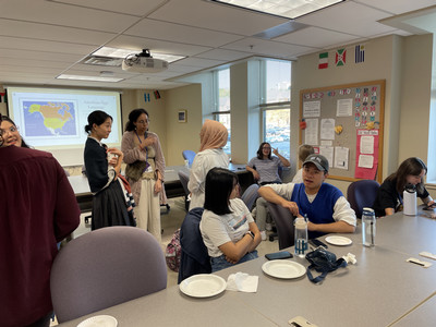 A group of students and TAs talking and eating snacks in the Language Learning Center.