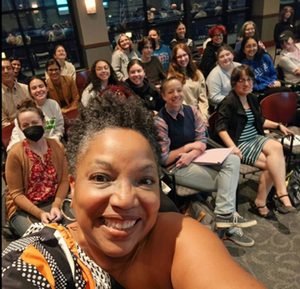 Novelist Yolanda Arroyo Pizarro taking a selfie with a group of people sitting in chairs behind her.