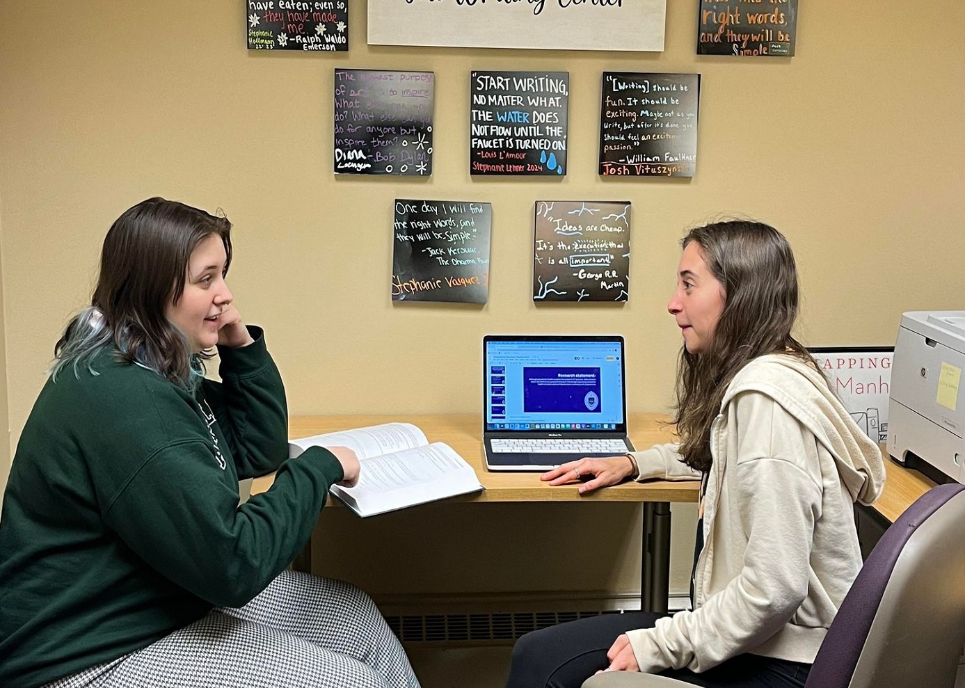 A writing center with a tutor facing a student while discussing a paper