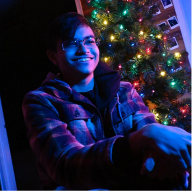 A photo of a man in front of a Christmas tree