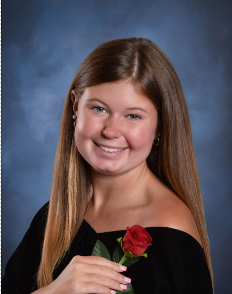 A girl with long blonde hair in a black blouse with a rose