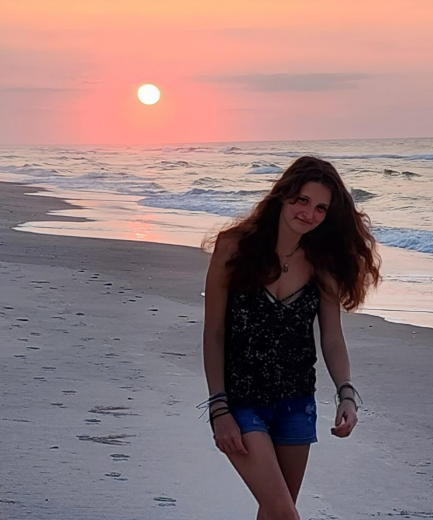 A girl walking on a beach at sunset