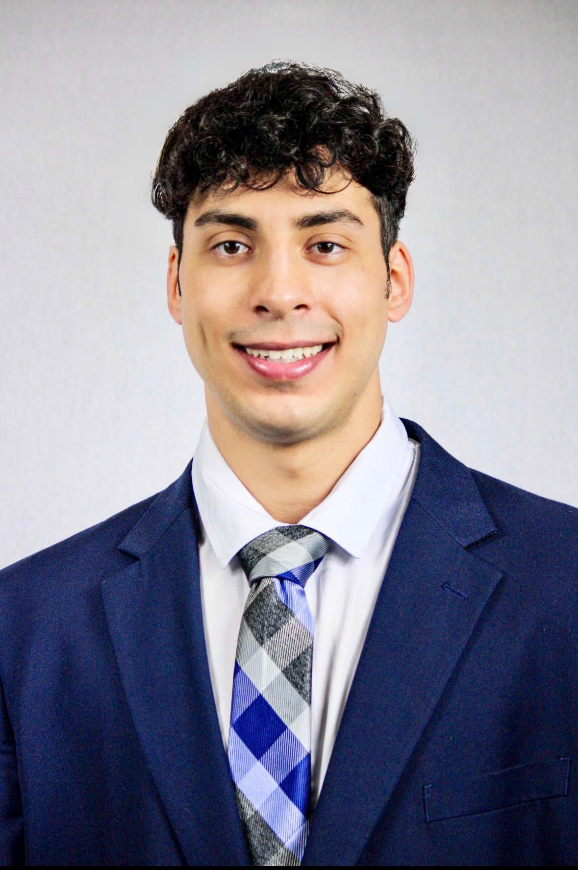 A man with short dark hair against a white background