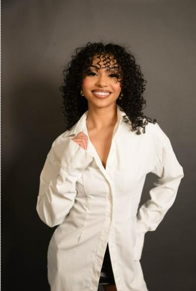 A girl with black curly hair in a white blouse