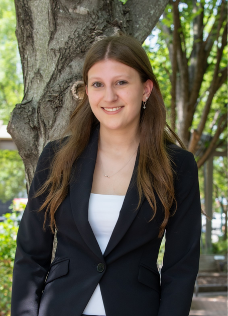 A young woman with a black jacket in front of a tree
