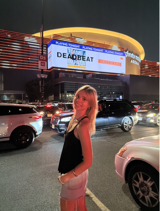 A young woman standing in front of a building in the evening