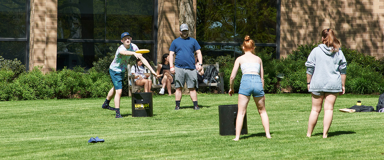 Four students playing a Frisbee game on the grass