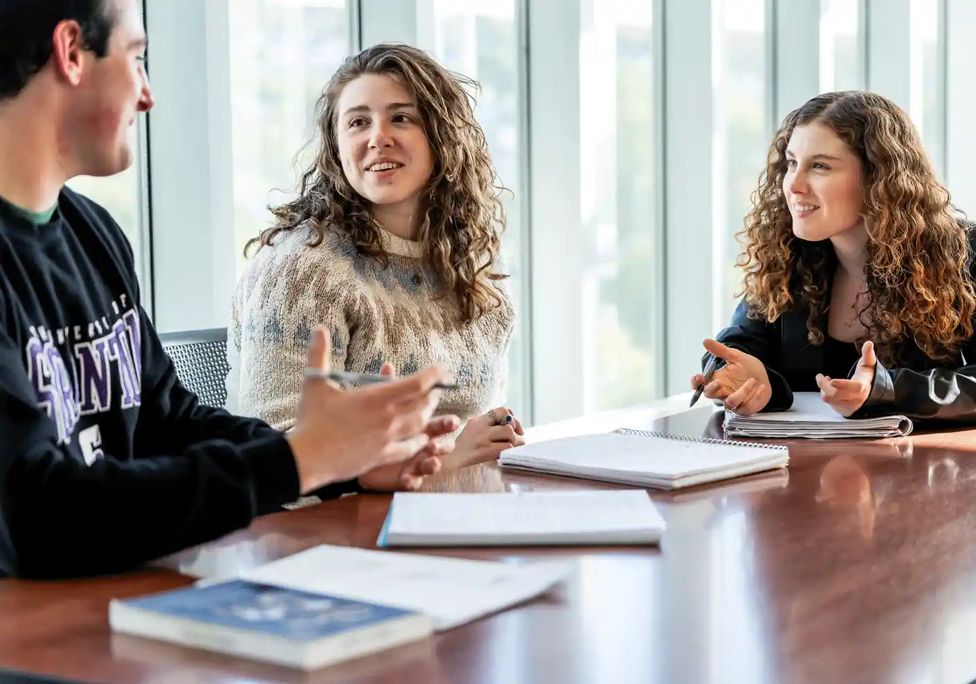 Students sitting at a table with open notebooks.