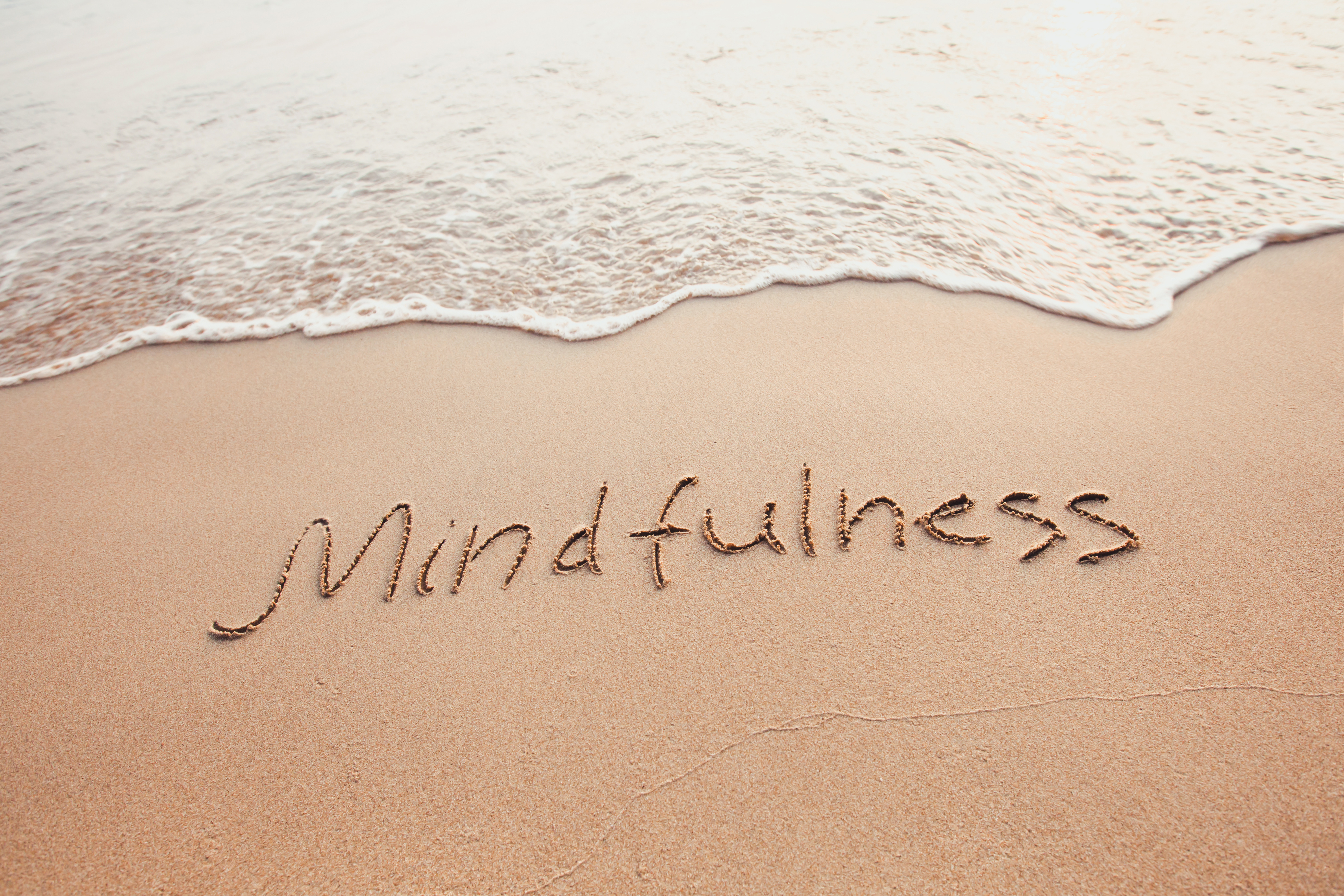 sand with ocean with the word mindfulness written out